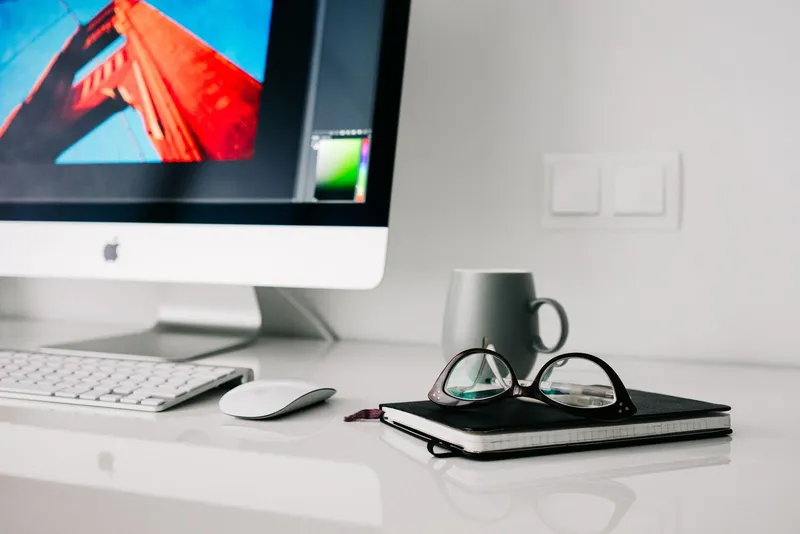 Gafas apoyadas en un escritorio de trabajo con ordenador
