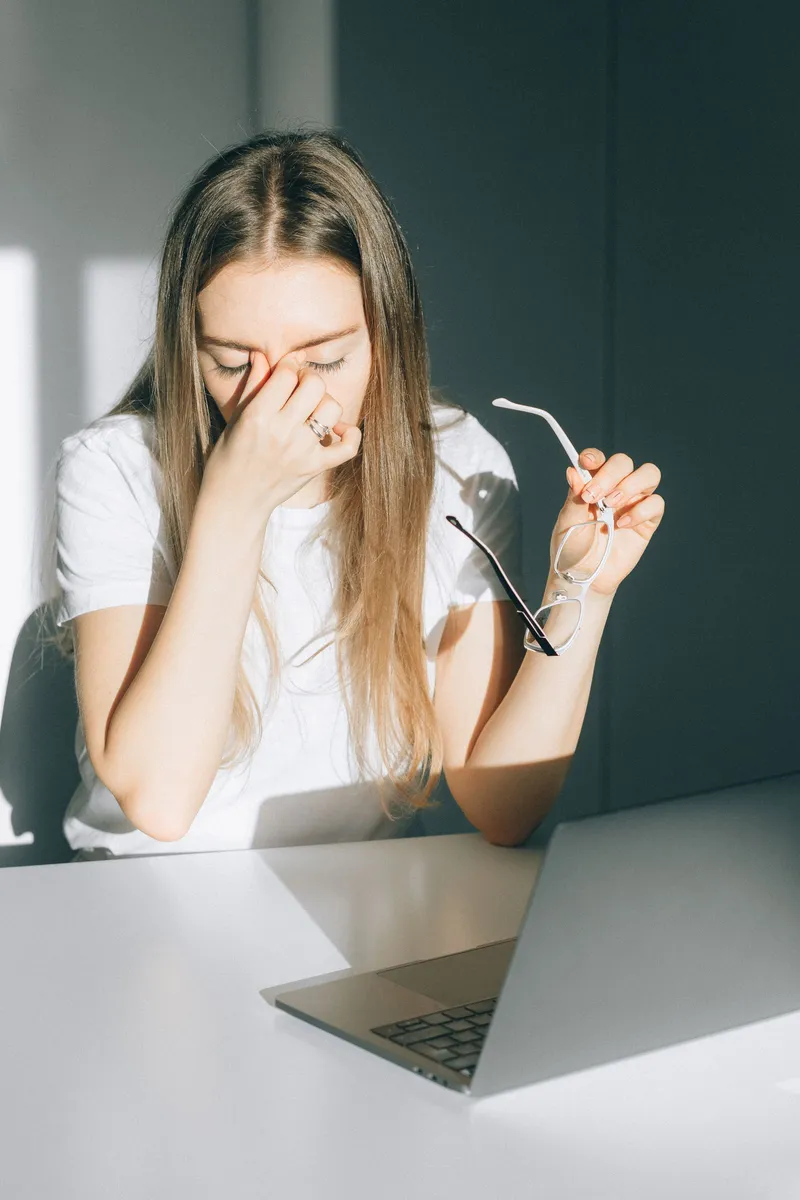 Mujer con gafas cansada frente a la pantalla del ordenador