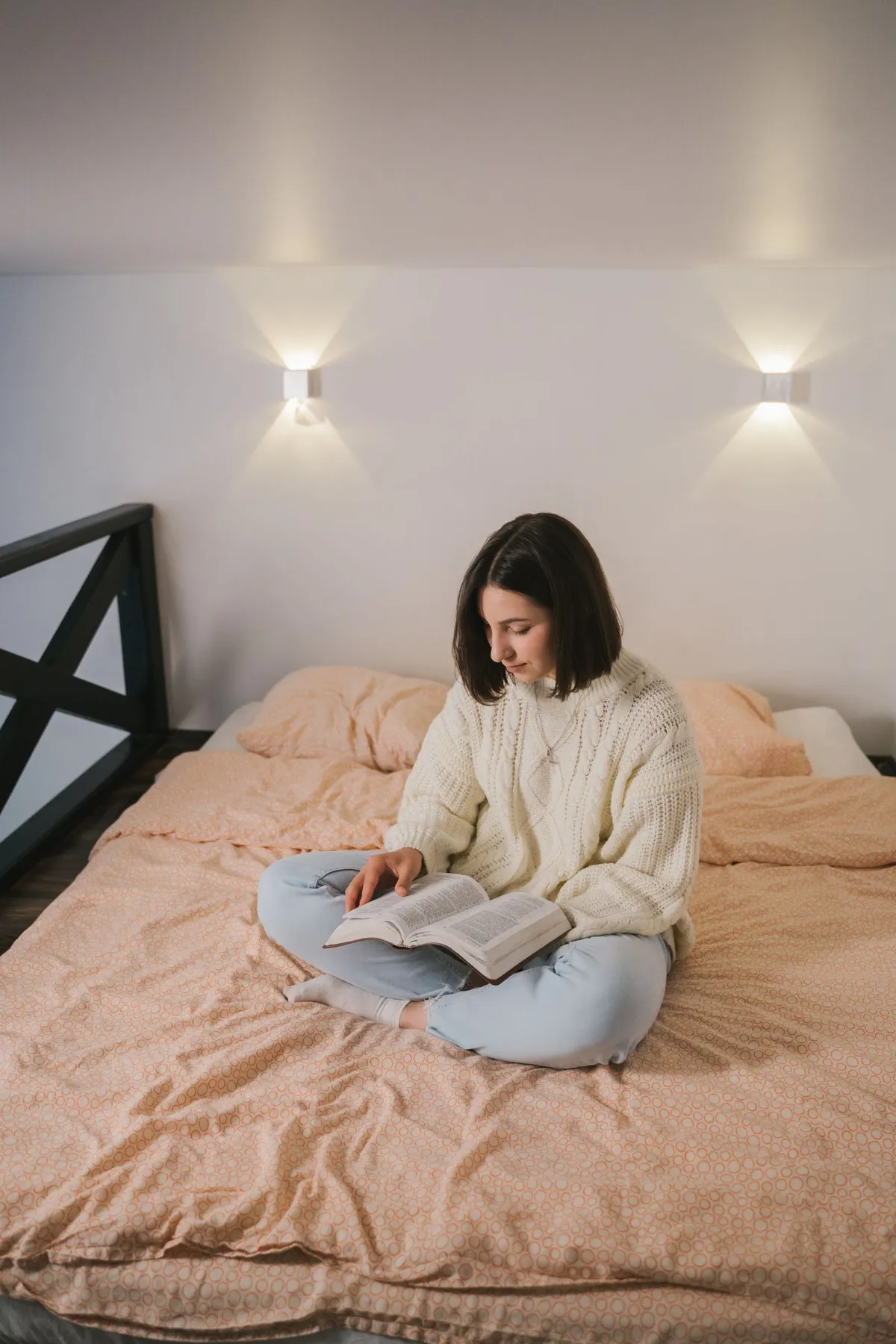 Mujer leyendo un libro en papel en la cama por la noche