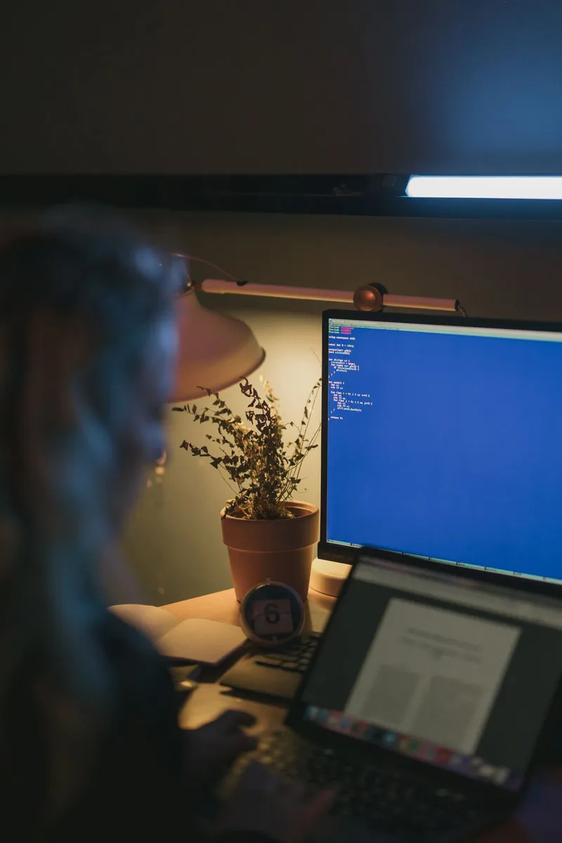 Persona trabajando en el ordenador de noche iluminada por la pantalla