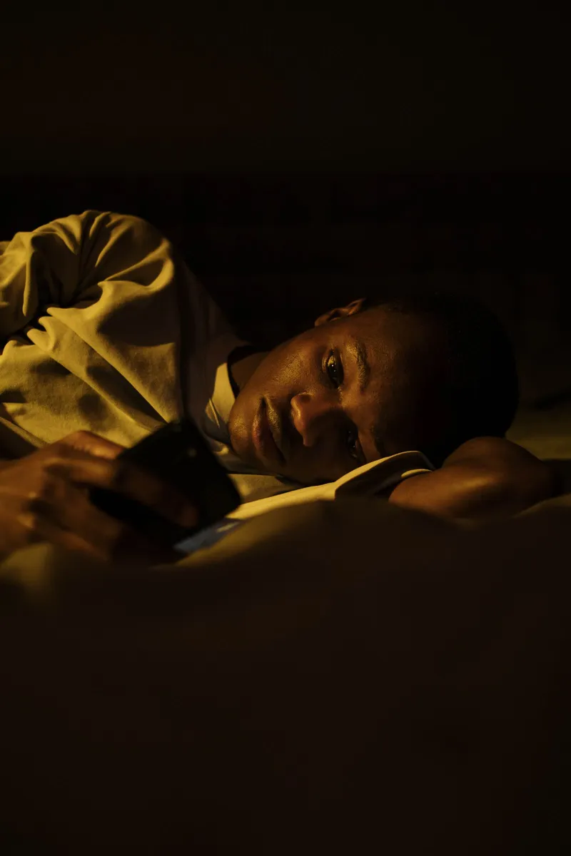 Hombre en la cama a oscuras con la cara iluminada por la pantalla del móvil